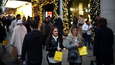 People carry shopping bags as they walk past Christmas themed shop displays on Oxford Street in London, on December 4, 2022. (Reuters)