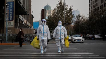 Pandemic prevention workers in protective suits cross a street as coronavirus disease (COVID-19) outbreaks continue in Beijing, December 9, 2022. (Reuters)