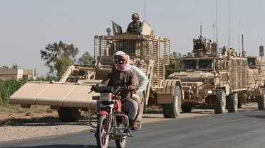 FILE - In this July 26, 2017 file photo, people ride past U.S. armored vehicles in Raqqa, Syria. Amnesty International, an international rights group, urged the U.S.-led military coalition battling the Islamic State group to investigate airstrikes that killed civilians in the campaign to liberate the Syrian city of Raqqa from the extremists. Amnesty said Tuesday, Aug. 7, 2018, that the U.S.-coalition's admission last month that it killed 78 more civilians than previously reported in the 2017 assault on Raqqa was just the tip of the iceberg. (AP Photo/Hussein Malla, File)