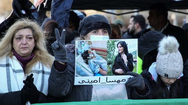 A protester holds a picture of 22-year-old Iranian Kurd Mahsa Amini during a protest in front of the Iranian consulate in Frankfurt am Main, on December 16, 2022. (AFP)