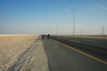 Julia and Tilmann Schöllnhammer cycle along the highway in the western United Arab Emirates, on their way to the border with Saudi Arabia. (Marco Ferrari/Al Arabiya English)