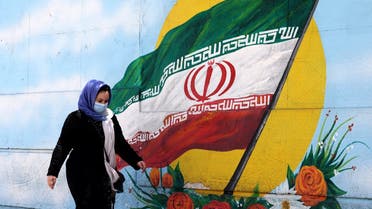 An Iranian woman walks past a mural displaying Iran’s national flag in Tehran, on June 17, 2021. (AFP)