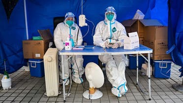 Health workers wait for people to scan a health code to test for the COVID-19 coronavirus in the Jing’an district in Shanghai on December 22, 2022. (AFP)