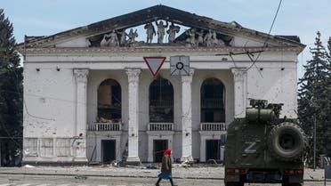 A woman walks next to bombed theatre in Mariupol. (Reuters)