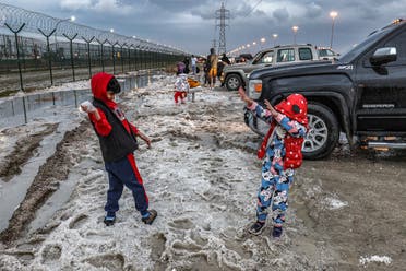 Children toss handfuls of hail particles picked up off the side of a road after a storm in the Umm al-Haiman district, about 55 kilometres south of Kuwait City, on December 27, 2022. (AFP)