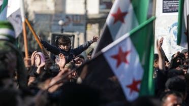 Demonstrators raise Syrian opposition flags and placards as they rally against a potential rapprochement between Ankara and the Syrian regime, on December 30, 2022, in the opposition-held city of al-Bab, on the border with Turkey, in Syria’s northern Aleppo province. (AFP)