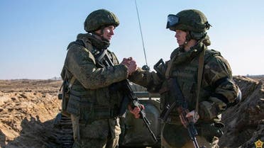 This handout video grab taken and released by the Belarussian Defense Ministry on February 19, 2022, shows Russian (L) and Belarus (R) soldiers shaking hands during joint exercises of the armed forces of Russia and Belarus. (AFP)
