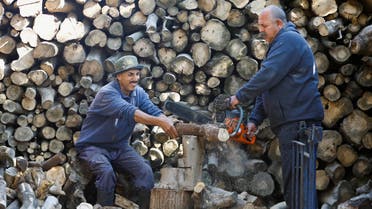 A Palestinian man Samir Hejji and his son cut wood for sale, in Gaza City, December 28, 2022. (Reuters)