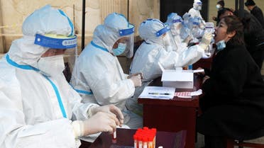 Medical workers in protective suits collect swabs for nucleic acid testing during a mass testing following cases of the coronavirus disease (COVID-19) in Xuchang, Henan province, China January 6, 2022. (Reuters)