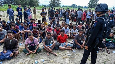 A policemen watches Rohingya refugees upon their arrival by a boat in Lamnga beach, Aceh province in Indonesia on January 8, 2023. A wooden boat carrying nearly 200 Rohingya refugees, a majority of them women and children, landed on Indonesia’s western coast on January 8, police said. (AFP)