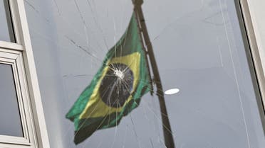 Brazil's flag is reflected on a broken window, after the supporters of Brazil's former President Jair Bolsonaro participated in an anti-democratic riot at Planalto Palace, in Brasilia, Brazil, January 9, 2023. (Reuters)