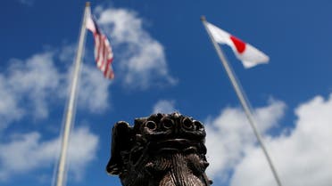 The US (L) and Japanese national flags are hoisted next to a traditional Okinawan Shisa statue at the US Marine’s Camp Foster in Ginowan, on the southern island of Okinawa, Japan June 18, 2016. (Reuters)