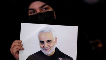 An Iranian woman holds a picture of Qassem Soleimani, during a ceremony to mark the second anniversary of the killing of senior Iranian military commander General Qassem Soleimani in a US attack, in Tehran, Iran, on January 3, 2022. (West Asia News Agency via Reuters)