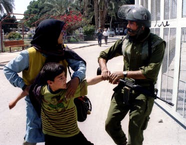 A Palestinian mother struggles to keep her young son from being arrested by an Israeli soldier. (File photo: Reuters)