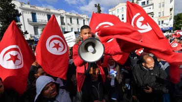 Tunisian demonstrators raise national flags and protest placards as they take to the streets of the capital Tunis, on January 14, 2023, to protest against their president. (AFP)