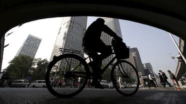 A man rides his bicycle across the street under the Guomao bridge at the Central Business District in Beijing. (Reuters)