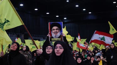 Hezbollah supporters wave national (R) and party (yellow) flags during a televised speech by Hassan Nasrallah (portrait) in Beirut's southern suburbs on Jan. 3, 2023. (AFP)