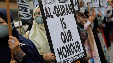 A woman holds a placard that reads “Al-Quran is our honour” during a protest in front of the Swedish embassy after Rasmus Paludan, leader of Danish far-right political party Hard Line burned a copy of the Koran near the Turkish Embassy in Stockholm, in Kuala Lumpur, Malaysia, on January 27, 2023. (Reuters)