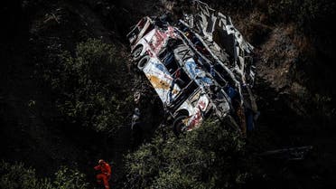 A rescuer stands next to the wreckage of a bus that plunged off a cliff in Matucana, east from Lima on August 31, 2021. (AFP)