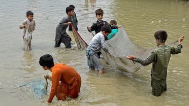 Flood-affected children catch fish along a flooded street after heavy monsoon rains in Charsadda district of Khyber Pakhtunkhwa province on September 11, 2022. (Photo by Abdul MAJEED / AFP)