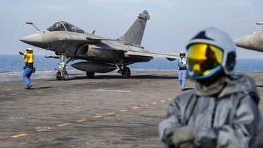 A French navy aircraft handling officer (L) signals to a Rafale aircraft fighter jet on the flight deck as a firefighter (R) looks on, on the French aircraft carrier Charles de Gaulle, sailing between the Suez canal and the Red Sea on December 19, 2022. (AFP)