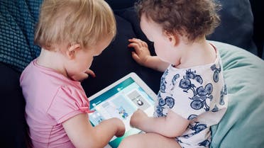 Infants using an iPad. (Unsplash, Jelleke Vanooteghem)