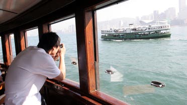 سائح يلتقط صوراً خلال رحلة في هونغ كونغ (رويترز)