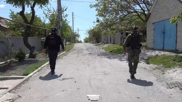 Members of the security forces walk on a street as they evacuate civilians, in Bilohorivka, Ukraine, in this still image taken from a handout video released May 20, 2022. (Reuters) 
