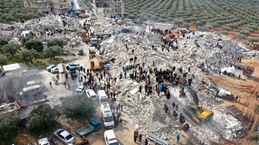 This aerial view shows residents, aided by heavy equipment, searching for victims and survivors amidst the rubble of collapsed buildings following an earthquake in the village of Besnia near the twon of Harim, in Syria's noryhwestern Idlib province on the border with Turkey, on February 6, 2022. (AFP)