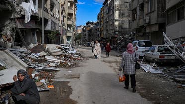 People walk along a street strewn with debris as they look for relatives in Hatay, Turkey on February 7, 2023, a day after a 7,8-magnitude earthquake struck the country’s southeast. (AFP)
