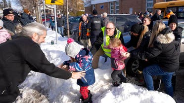 Parents and their children are loaded onto a warming bus as they wait for news after a bus crashed into a daycare centre in Laval, Quebec, on Wednesday, Feb. 8, 2023. (AP)
