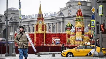 A man crosses a street in front of Kievsky railway terminal with the replicas of the Spasskaya tower of the Kremlin and St. Basil’s cathedral in front of it in Moscow on February 8, 2023. (AFP)