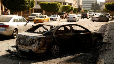 A car burned during clashes remains on a street in the Libyan capital of Tripoli, Sunday, Aug. 28 2022. Deadly clashes broke out Saturday in Libya's capital between militias backed by its two rival administrations, portending a return to violence amid a long political stalemate. (AP Photo/Yousef Murad)