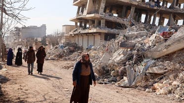 Residents walk along destroyed buildings, as search and rescue operations continue days after a deadly earthquake hit Turkey and Syria, in the town of Jindayris, in the opposition-held part of Syria’s Aleppo province, on February 10, 2023. (AFP)