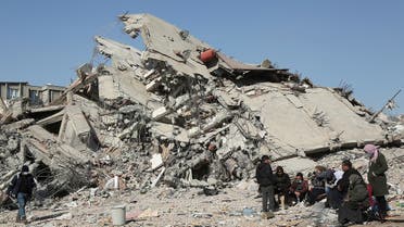 People sit and stand near a collapsed building, in the aftermath of the deadly earthquake, in Adiyaman, Turkey, on February 12, 2023. (Reuters)
