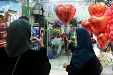 A woman takes a photo with her mobile phone as another holds a heart-shaped balloon as they shop at a florist ahead of Valentine's Day in Riyadh, Saudi Arabia February 13, 2021. (File photo: Reuters)
