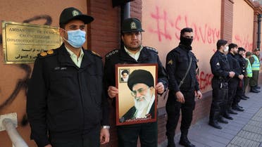 An Iranian police officer holds a picture of Supreme Leader Ali Khamenei during a protest to condemn the French magazine Charlie Hebdo for republishing cartoons insulting Khamenei, in front of the French Embassy in Tehran, Iran, January 8, 2023. (West Asia News Agency via Reuters)