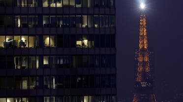 The Eiffel Tower lights the sky behind office lights illuminated at dusk in high rise buildings at La Defense business and financial district near Paris, France, December 5, 2022. (Reuters)