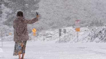 A visitor stands on a snow-covered road while taking a selfie in the Angeles National Forest near La Canada Flintridge, Calif., Thursday, Feb. 23, 2023. (AP Photo/Jae C. Hong)