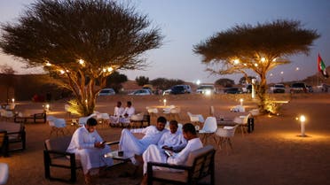 People use their mobiles as they sit at One Degree cafe, a popular destination for desert recreation as the winter season gets underway, at Dubai-Sharjah border, UAE, November 11, 2022. (Reuters)