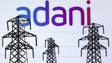 Electric power transmission pylon miniatures and Adani Green Energy logo are seen in this illustration. (Reuters)
