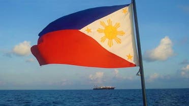 In this handout photo taken April 14, 2021, and received from the Philippine Coast Guard (PCG) April 15, a Philippine flag is displayed aboard a coast guard rubber boat as they patrol past Chinese vessels at Whitsun Reef, in the Spratly Islands. (Philippine coast Guard via AFP)