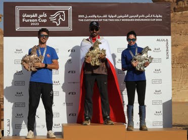 Spain's Omar Blanco (left), Bahrain's Mohammed Hashemi (center), and Spain's Maria Alvarez (right) pose with their trophies on the podium after the 2023 Custodian of the Two Holy Mosques Endurance Cup in Saudi Arabia's AlUla. 