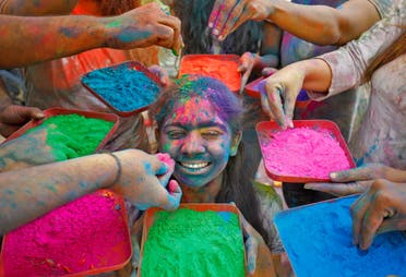 A girl reacts as coloured powder is applied on her face while posing for photographs during Holi celebrations in Ahmedabad, India, March 18, 2022. (Reuters)