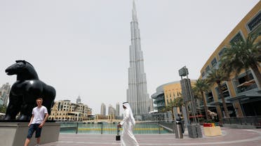 An Emirati man walks past a tourist posing for a photo near the Burj Khalifa, the tallest tower in the world, in Dubai May 9, 2013.  (Reuters)