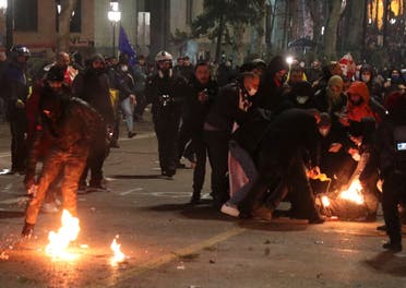 محتجون يقومون بإخماد نيران جراء الاشتباكات مع الشرطة في جورجيا (رويترز)