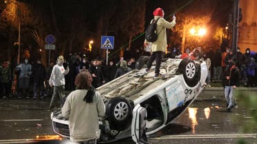 A person stands on an overturned car during a protest against a draft law on foreign agents, which critics say represents an authoritarian shift and could hurt Georgia's bid to join the European Union, in Tbilisi, Georgia, March 9, 2023. (Reuters)