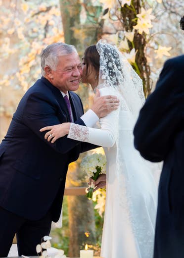 A handout picture released by Jordan's Royal Palace shows King Abdullah II congratulating his eldest daughter Princess Iman during her wedding ceremony with Jameel Alexander Thermiotis in Amman on March 12, 2023. (AFP)