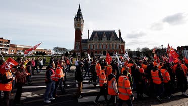 Protesters walk past the City Hall during a demonstration on a 8th day of strikes and protests across the country against the government's proposed pensions overhaul in Calais, on March 15, 2023. France faces another day of strikes over highly contested pension reforms which President appears on the verge of pushing through despite months of protests. As the legislation enters the final stretch in parliament, trade unions are set to make another attempt to pressure the government and lawmakers into rejecting the proposed hike in the retirement age to 64. (Photo by Sameer Al-Doumy / AFP)