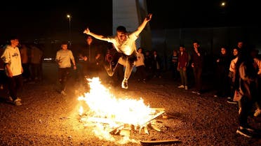 An Iranian jumps over a bonfire during the Wednesday Fire feast, or Chaharshanbeh Suri, held annually on the last Wednesday eve before the Spring holiday of Nowruz, in Tehran on March 14, 2023 ahead of the Nowruz New Year festival. (AFP)